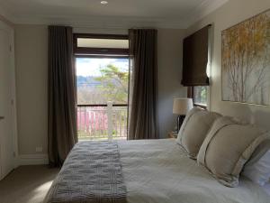um quarto com uma cama e uma grande janela em La Casétta em Leura