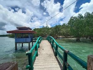 a wooden pier with a gazebo on the water at RedDoorz Plus @ Costa Roca Balamban in Cebu City