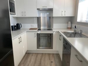 a white kitchen with a sink and a stove at Stylish Oasis in central city in Christchurch