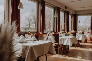 a restaurant with white tables and chairs and windows at Hotel zur Treene in Schwabstedt