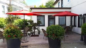 a patio with red umbrellas and chairs and tables at Hotel Niedersachsen in Quakenbrück