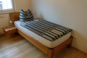 a small bed with a striped blanket on top of it at Gästehaus Familie John in Veitsbronn