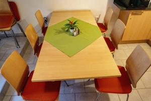 uma mesa de madeira com cadeiras e uma planta sobre ela em Gästehaus Familie John em Veitsbronn
