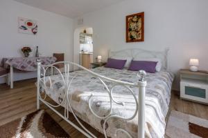 a bedroom with a white bed with purple pillows at Francisko in Grižane