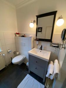 a bathroom with a sink and a toilet and a mirror at Hotel Niedersachsen in Quakenbrück