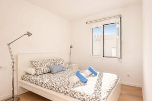a white bedroom with a bed with blue pillows at Villa Ca Na Margarita by Villa Plus in Cala Blanca