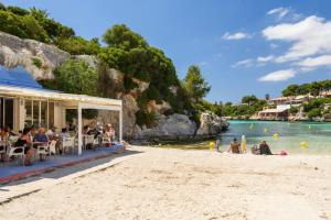 a beach with a restaurant and people on the beach at Villa Ca Na Margarita by Villa Plus in Cala Blanca