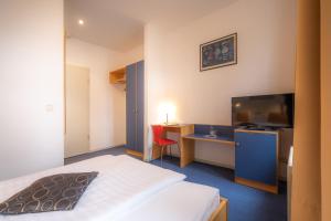 ein Hotelzimmer mit Bett und Schreibtisch mit Fernseher in der Unterkunft Alt-Weimar in Weimar + 9 Fotos