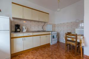 - une cuisine avec des placards blancs, une table et un réfrigérateur dans l'établissement FILIPOVIC, à Novi Vinodolski