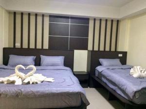 two beds with white towels on them in a bedroom at Pangviman Residence in Ban Prong Phra Bat Nok (1)