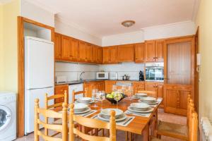 a kitchen with a wooden table and a white refrigerator at Villa Xaloc Blanes by Villa Plus in Cala Blanca