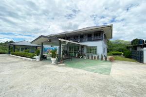 ein großes weißes Haus mit einem Tennisplatz davor in der Unterkunft OYO Home 90230 Dh Residence in Kota Belud