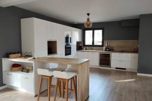 uma cozinha com armários brancos, uma mesa e bancos em Agréable Villa Domaine du Golf Piscine CHAUFFEE em Biscarrosse