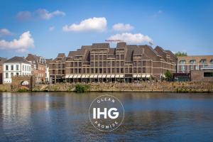 ein großes Gebäude mit einem Schild in der Mitte eines Flusses in der Unterkunft Crowne Plaza Maastricht, an IHG Hotel in Maastricht