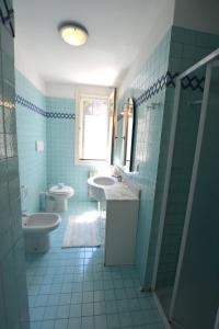 a blue tiled bathroom with two sinks and a toilet at Lignano Pineta exclusiv in Lignano Sabbiadoro