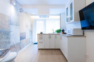 a white kitchen with a sink and a tv at Lapwing Residence Sopot in Sopot