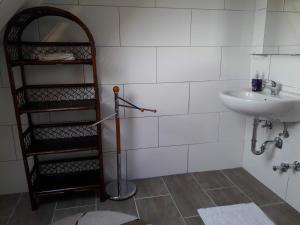 a white tiled bathroom with a sink and a shelf at Monteurwohnungen Lerch Santos in Mönchengladbach