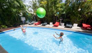 two children playing in a swimming pool with a green balloon at Hôtel les Bougainvilliers in Saint-Gilles-les-Bains