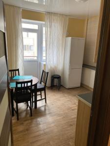 Apartments at Okruzhnaya 3 في زيلينوغرادسك: مطبخ صغير مع طاولة وكراسي وثلاجة