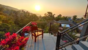 a balcony with a chair and flowers on it at บ้านภูคำฟ้า ดอยปู่ไข่ Baan Phu Kham Fah in Chiang Rai