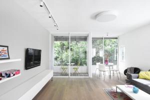 a white living room with a couch and a tv at Light Ivory by HolyGuest in Tel Aviv