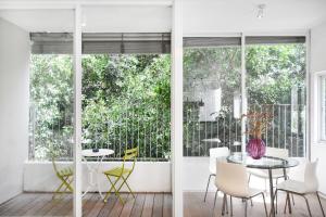 a dining room with a table and chairs and windows at Light Ivory by HolyGuest in Tel Aviv