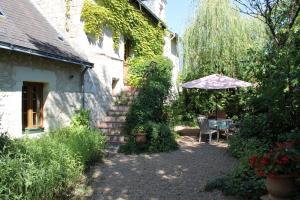 a patio with an umbrella and a table and chairs at La Closerie in Saint-Philbert-du-Peuple