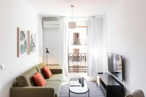 een woonkamer met een bank en een tv bij Aspasios Calle Mayor Apartments in Madrid