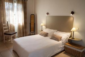 sypialnia z dużym białym łóżkiem i krzesłem w obiekcie Erbalunga - Résidence Les Bosquets - Cap corse Location w mieście Brando
