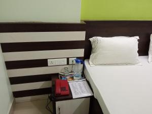 a hotel room with a bed and a night stand with a phone at Hotel Viraat Inn in Gaya