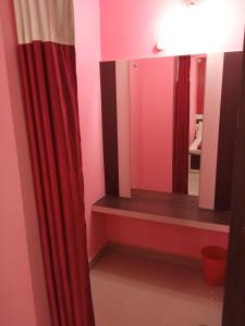 a bathroom with a red curtain and a mirror at Hotel Viraat Inn in Gaya