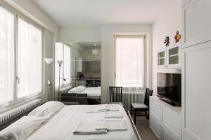 ein weißes Schlafzimmer mit einem Bett und einem TV in der Unterkunft The perfect one - Studio apt in Città Studi in Mailand