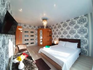 a bedroom with a bed and a table and a tv at Apartament on Krylova 19 in Bobruisk