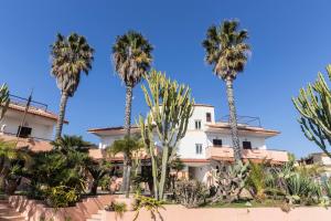 a group of palm trees in front of a building at Residence Esmeraldo in Capo Vaticano