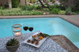 a table with food and wine glasses next to a swimming pool at College Lodge in Bloemfontein