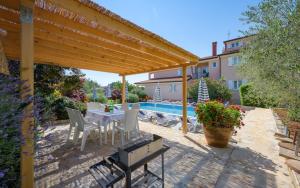 a patio with a table and chairs under a wooden pergola at Villa Franka 113 in Bašanija
