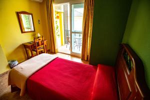 1 dormitorio con 1 cama roja en una habitación verde en Hotel Arunda II, en Ronda