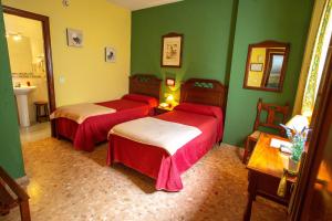 zwei Betten in einem Zimmer mit grünen Wänden in der Unterkunft Hotel Arunda II in Ronda