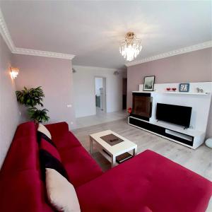 a living room with a red couch and a tv at Centre-Port apartment in Kherson