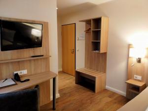 a room with a desk and a flat screen tv at Hotel Xtra Gleis in Hörstel