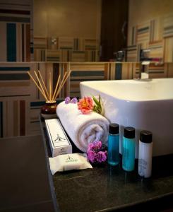 a bathroom with a sink and towels and flowers on a counter at Eiffel Suites - Kammanahalli in Bangalore