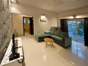 sala de estar con sofá verde y mesa en Eiffel Suites - Kammanahalli, en Bangalore