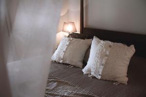 1 dormitorio con 1 cama con almohadas blancas y lámpara en Masseriola Antiche Fogge, en Fasano