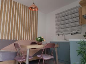 a kitchen with a table and two pink chairs at Galazia Thea Apartments in Archangelos