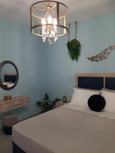 1 dormitorio con 1 cama blanca grande con lámpara de araña en Galazia Thea Apartments en Archangelos