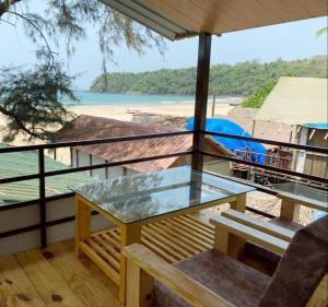 a glass table on a balcony with a view of the beach at Agonda Serenity Beach Villa in Agonda