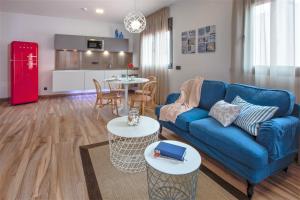 a living room with a blue couch and tables and a kitchen at Gran Marina Suites in Las Palmas de Gran Canaria