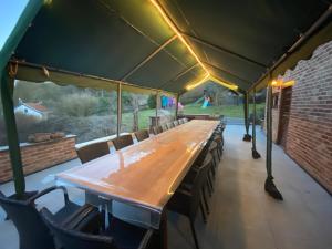 uma longa mesa de madeira e cadeiras sob uma tenda em Villa Agni em Barvaux