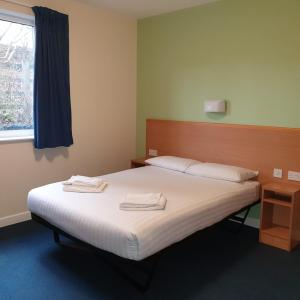 Glasney Rooms, University Campus Penryn في فالموث: غرفة نوم عليها سرير وفوط