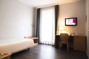 a hotel room with a bed and a desk and a television at Hotel Ristorante Primavera in Godega di SantʼUrbano